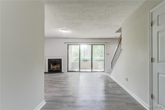 12255 Shore View Dr, Henrico, VA 23233 - unfurnished living room featuring wood finished floors, stairway, a fireplace with raised hearth, and a textured ceiling