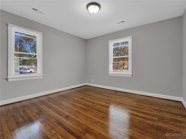 unfurnished room with wood finished floors, baseboards, and visible vents