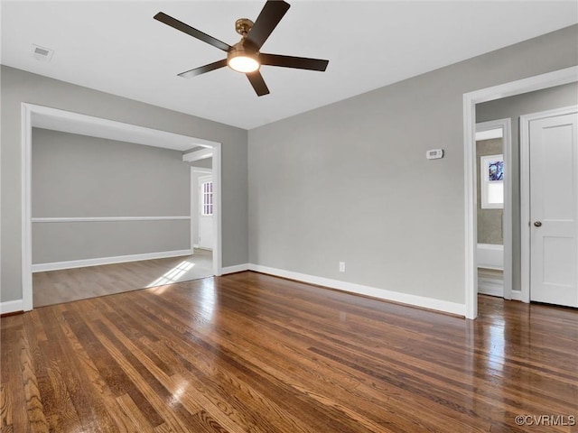 spare room with baseboards, visible vents, a ceiling fan, and wood finished floors