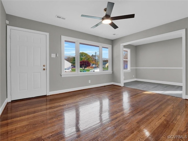interior space with baseboards, visible vents, wood finished floors, and a ceiling fan