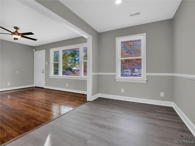 unfurnished room with a ceiling fan, wood finished floors, baseboards, and visible vents