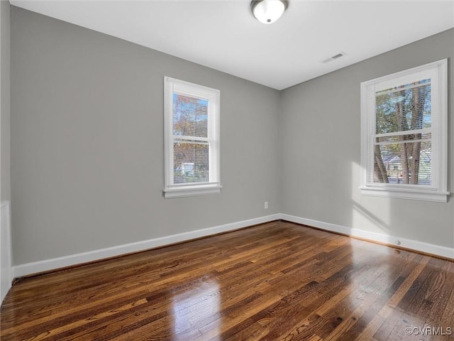 unfurnished room featuring baseboards, a healthy amount of sunlight, and visible vents