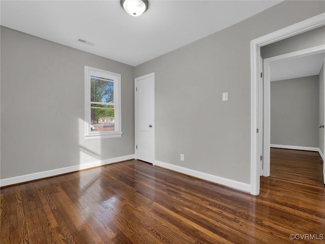 spare room with baseboards, visible vents, and wood finished floors