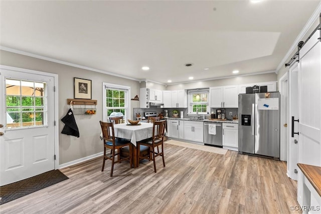 kitchen with appliances with stainless steel finishes, a barn door, a sink, and a healthy amount of sunlight