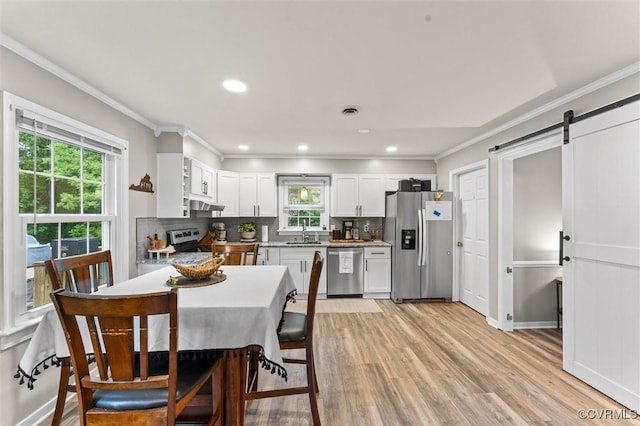 kitchen with crown molding, stainless steel appliances, a barn door, and backsplash