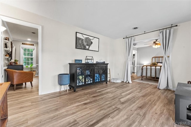 living area featuring a ceiling fan, baseboards, visible vents, and light wood-type flooring
