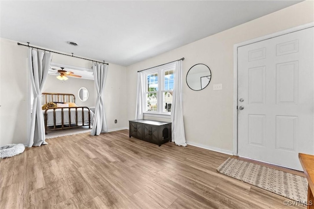 foyer entrance with baseboards, ceiling fan, and wood finished floors