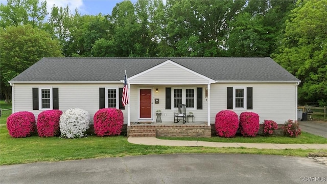 single story home with a porch, a shingled roof, and a front lawn