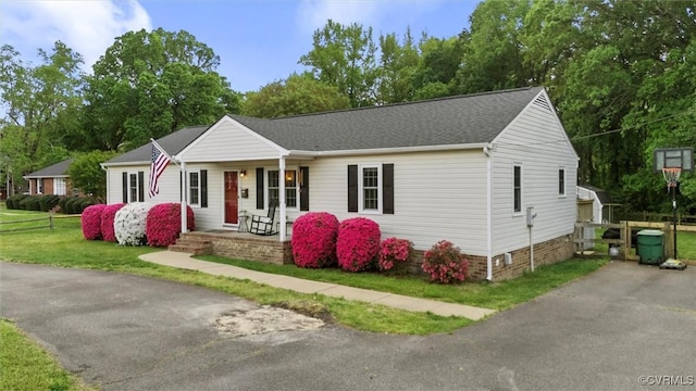 ranch-style house featuring roof with shingles, covered porch, crawl space, and a front yard