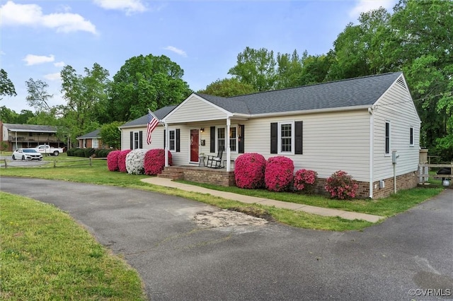 ranch-style home with covered porch, a shingled roof, crawl space, and a front yard