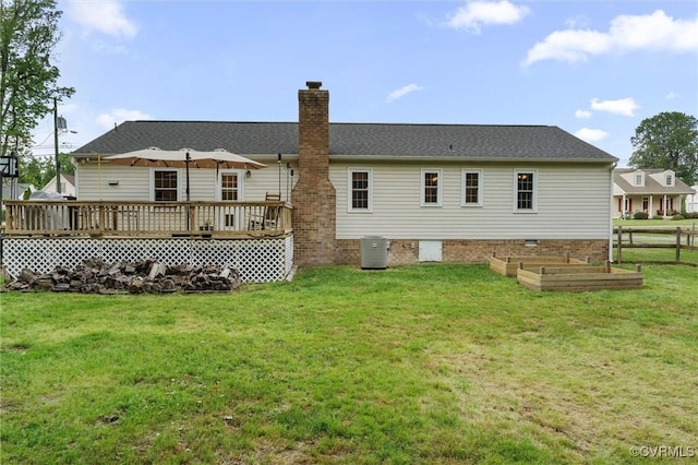 rear view of property featuring a deck, a chimney, cooling unit, a garden, and a lawn