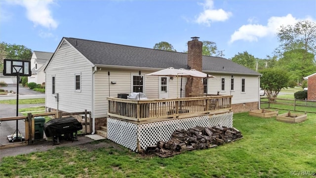 rear view of house featuring fence, a deck, a vegetable garden, a chimney, and a yard