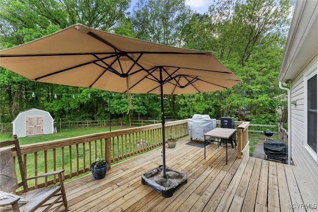 wooden terrace with a storage unit, an outdoor structure, a lawn, and a fenced backyard