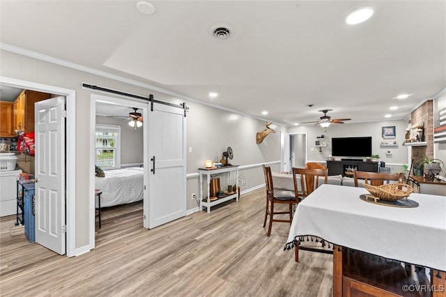 dining area featuring ceiling fan, crown molding, a barn door, light wood finished floors, and recessed lighting