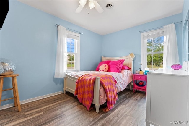 bedroom with multiple windows, a ceiling fan, wood finished floors, and visible vents