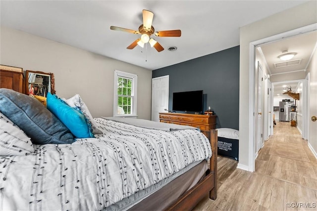 bedroom featuring ceiling fan, stainless steel fridge, light wood-style flooring, attic access, and baseboards