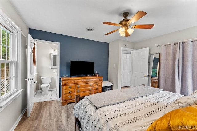 bedroom featuring visible vents, baseboards, ensuite bathroom, ceiling fan, and light wood-style flooring