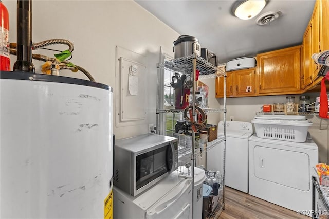 laundry area featuring visible vents, wood finished floors, washer and dryer, cabinet space, and water heater