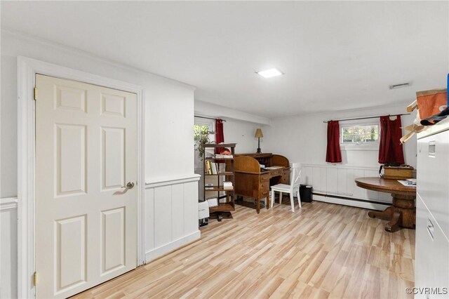 office area featuring baseboard heating, a wealth of natural light, and light wood finished floors