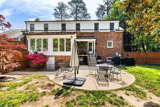 back of house featuring brick siding, a patio, a fenced backyard, and a chimney