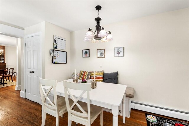 dining space featuring a baseboard heating unit, wood finished floors, and an inviting chandelier