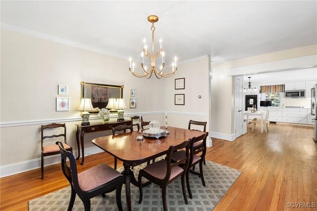 dining space featuring light wood-style flooring, baseboards, an inviting chandelier, and ornamental molding