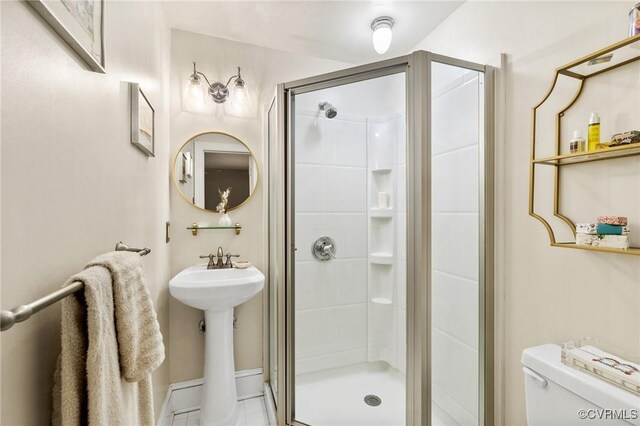 full bath featuring toilet, baseboards, a sink, and a stall shower