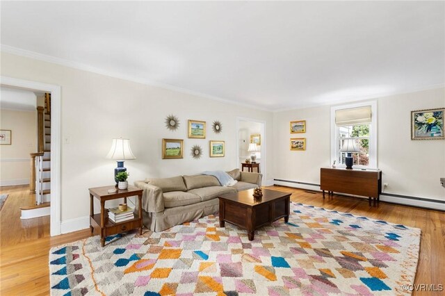 living area featuring a baseboard radiator, crown molding, and light wood finished floors