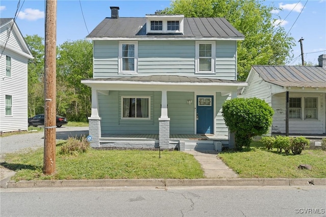 american foursquare style home featuring a standing seam roof, a front yard, covered porch, and metal roof