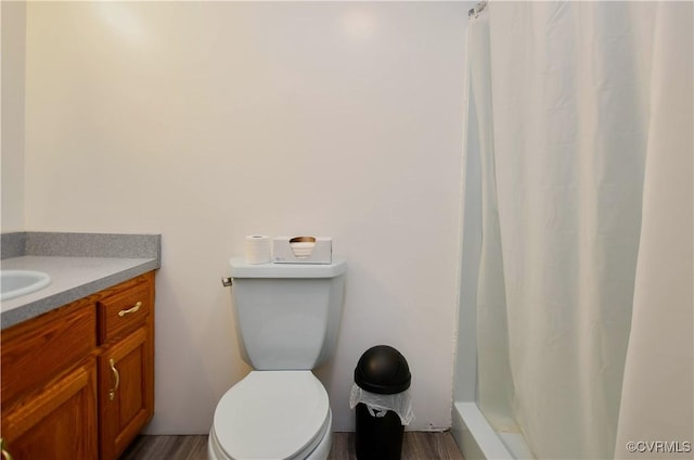 bathroom with a shower with curtain, wood finished floors, toilet, and vanity