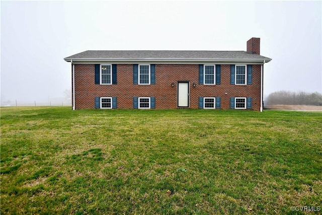 view of front of house featuring a chimney, a front lawn, and brick siding