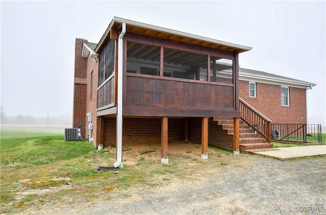 back of house featuring cooling unit, brick siding, a sunroom, and stairs