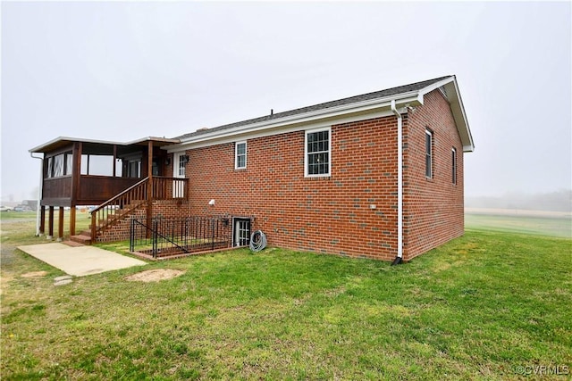 back of property with a lawn, brick siding, and a sunroom