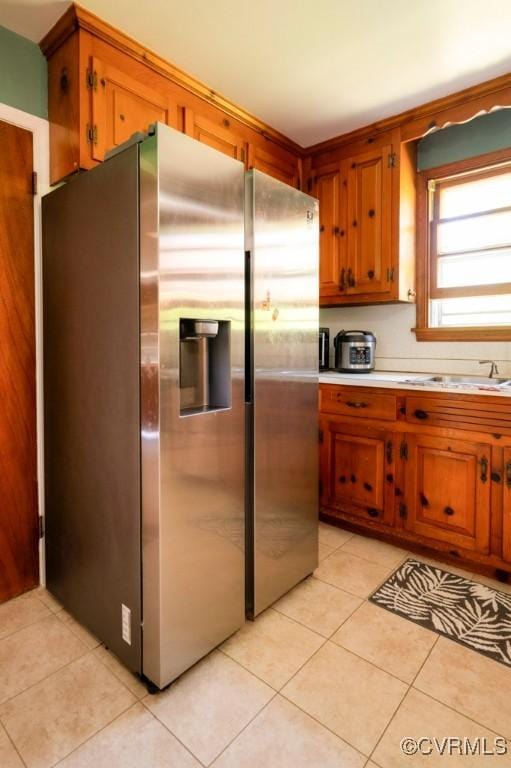 8186 Signal Hill Rd, Richmond, VA 23111 - kitchen with light tile patterned floors, a sink, light countertops, stainless steel refrigerator with ice dispenser, and brown cabinetry