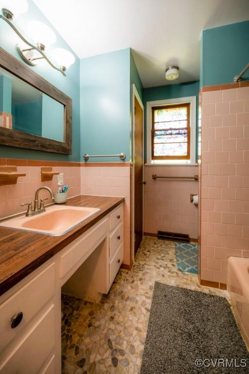 8186 Signal Hill Rd, Richmond, VA 23111 - bathroom featuring tile walls, vanity, bathing tub / shower combination, tile patterned floors, and wainscoting