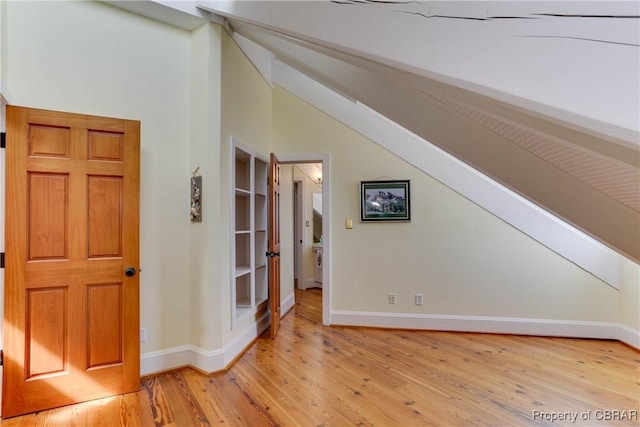 interior space featuring baseboards, light wood finished floors, and lofted ceiling