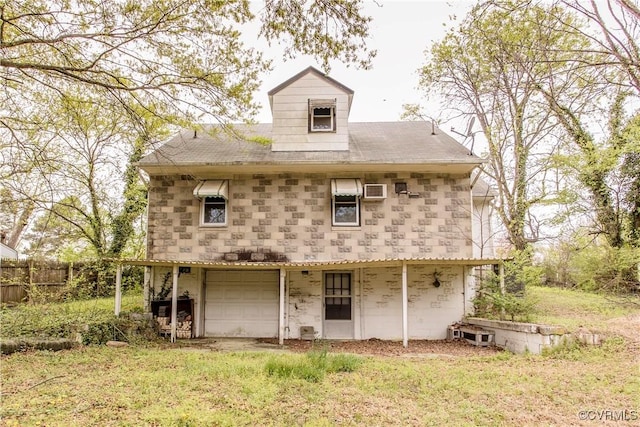 back of house featuring fence, a garage, stone siding, and a lawn