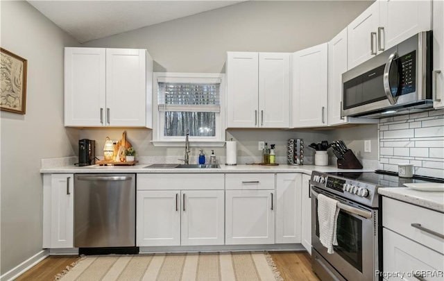 104 Martin Ln, Bohannon, VA 23021 - kitchen featuring appliances with stainless steel finishes, a sink, white cabinetry, and vaulted ceiling