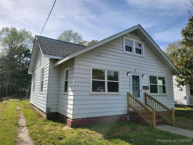 bungalow with entry steps and a shingled roof