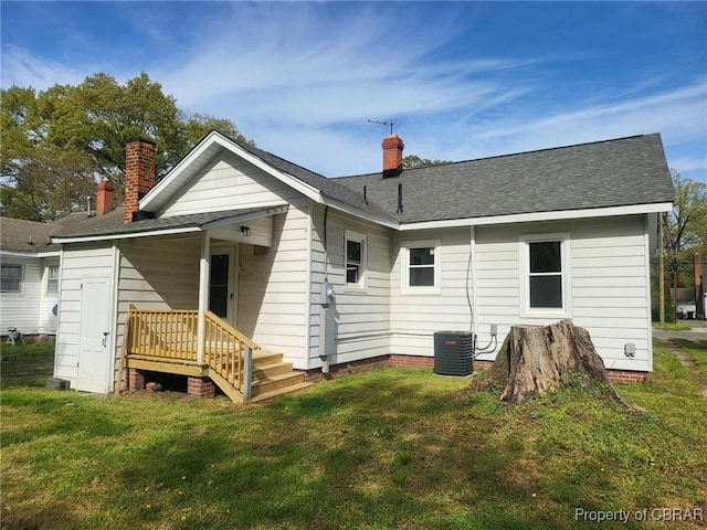 back of property with central AC, a chimney, and a lawn