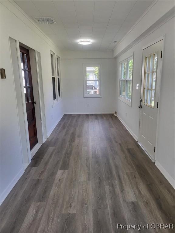 interior space with baseboards, dark wood finished floors, and visible vents