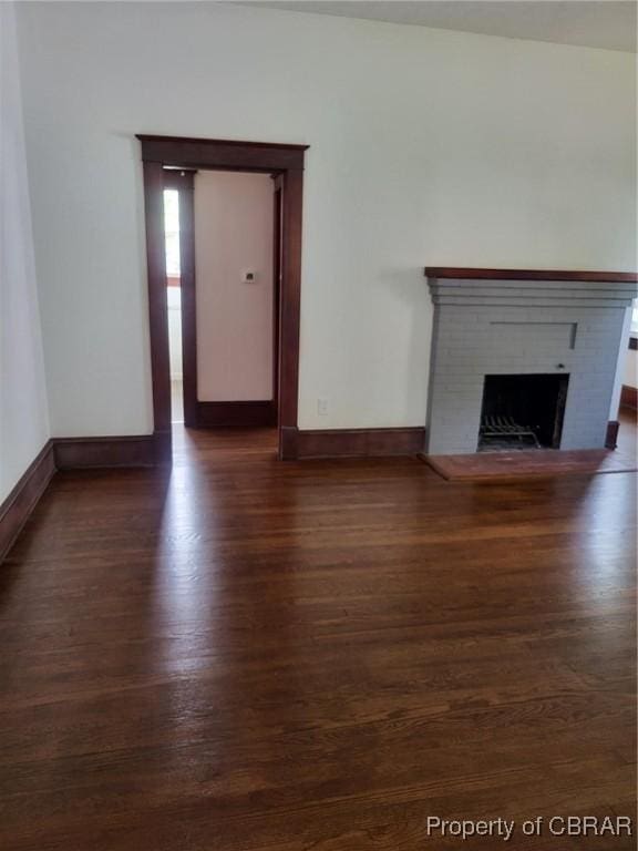 unfurnished living room featuring dark wood-style flooring, baseboards, and a fireplace
