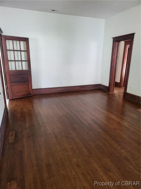 unfurnished room with baseboards and dark wood-style floors