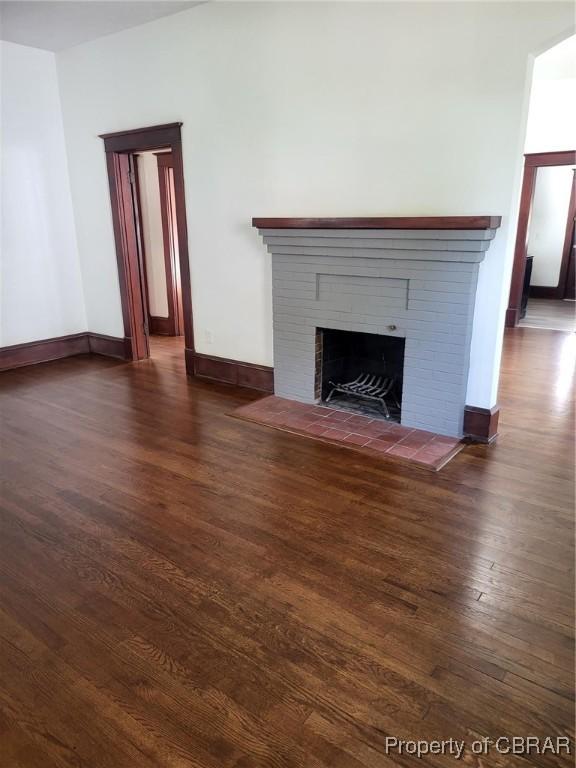 unfurnished living room featuring a fireplace, dark wood-type flooring, and baseboards
