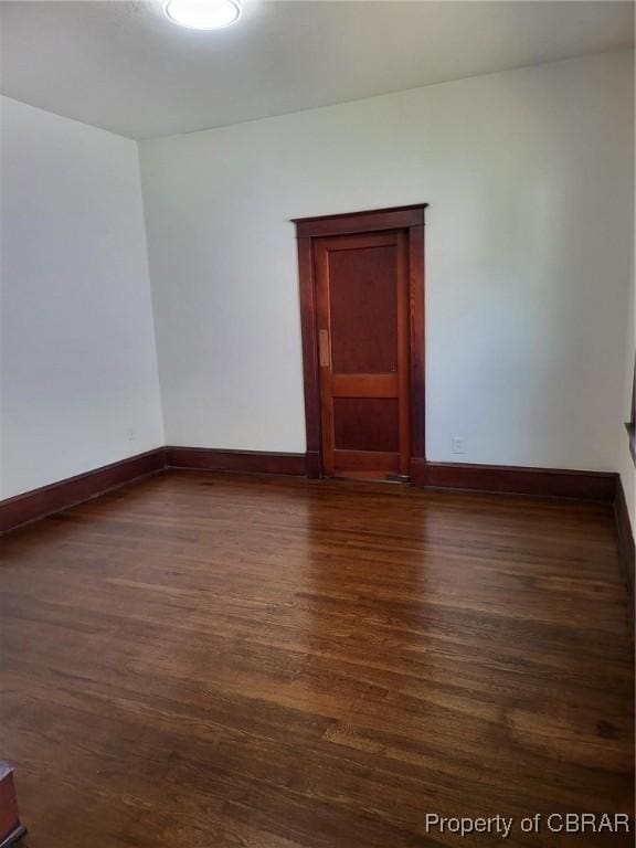 empty room with dark wood-style flooring and baseboards