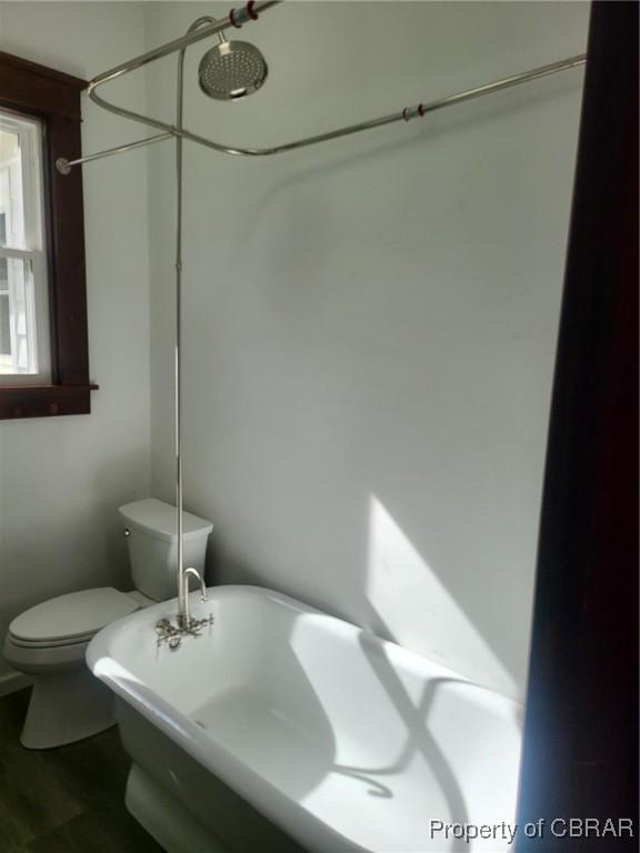 full bath featuring wood finished floors, toilet, and a washtub