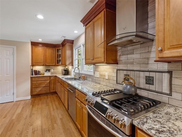 9208 Gayton Rd, Glen Allen, VA 23229 - kitchen with wall chimney exhaust hood, appliances with stainless steel finishes, light stone counters, light wood-style flooring, and brown cabinetry