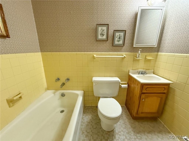 bathroom with toilet, a wainscoted wall, a garden tub, and wallpapered walls