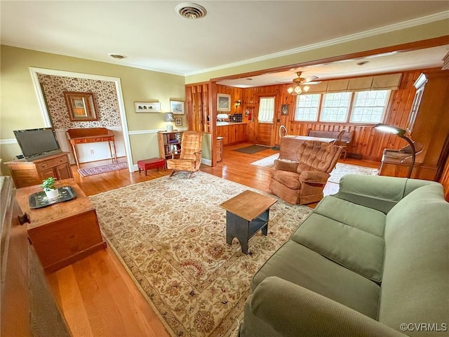 living room featuring ornamental molding, visible vents, ceiling fan, and wood finished floors
