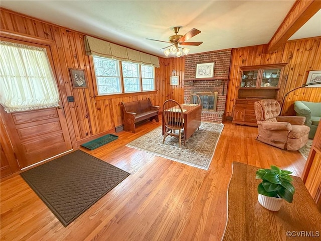 dining area featuring ceiling fan, light wood-type flooring, a baseboard radiator, and a brick fireplace